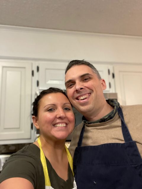 A photo of Heidi and Jason Clarke wearing aprons in the kitchen.